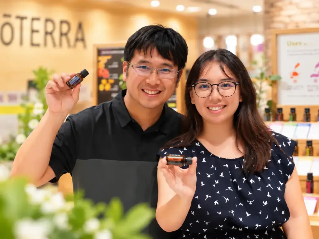 Holan and Cassy smiling and holding doTERRA essential oil bottles at a doTERRA Japan.